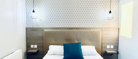 Een moderne hotelkamer met een groot bed, twee nachtkastjes en behang met een patroon.