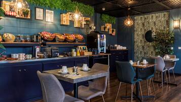 A restaurant with a blue wall, wooden counter, and green plants. There are tables and chairs for dining.