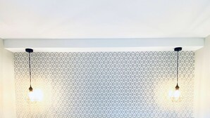 Une chambre d’hôtel avec deux lits, un papier peint à motifs et des lampes suspendues.