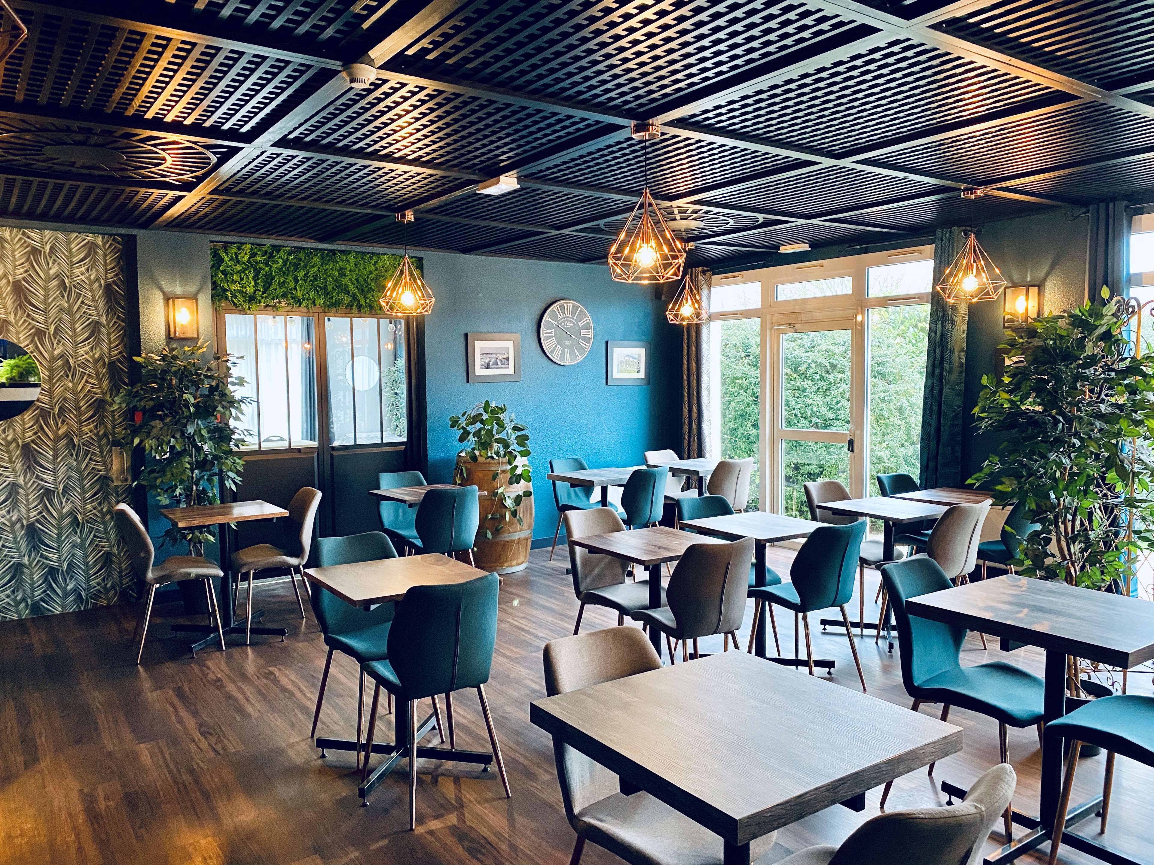 Ein modernes Restaurant mit Holztischen und -stühlen, großen Fenstern und dekorativen Deckenverkleidungen.