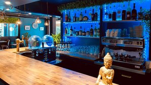 Un espace bar agrémenté d’une statue de Bouddha, d’étagères remplies de bouteilles d’alcool et d’une machine à café.