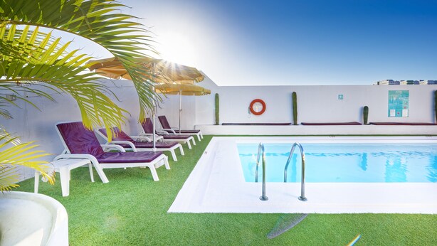 Uma área de piscina com cadeiras de sol brancas e piscina.