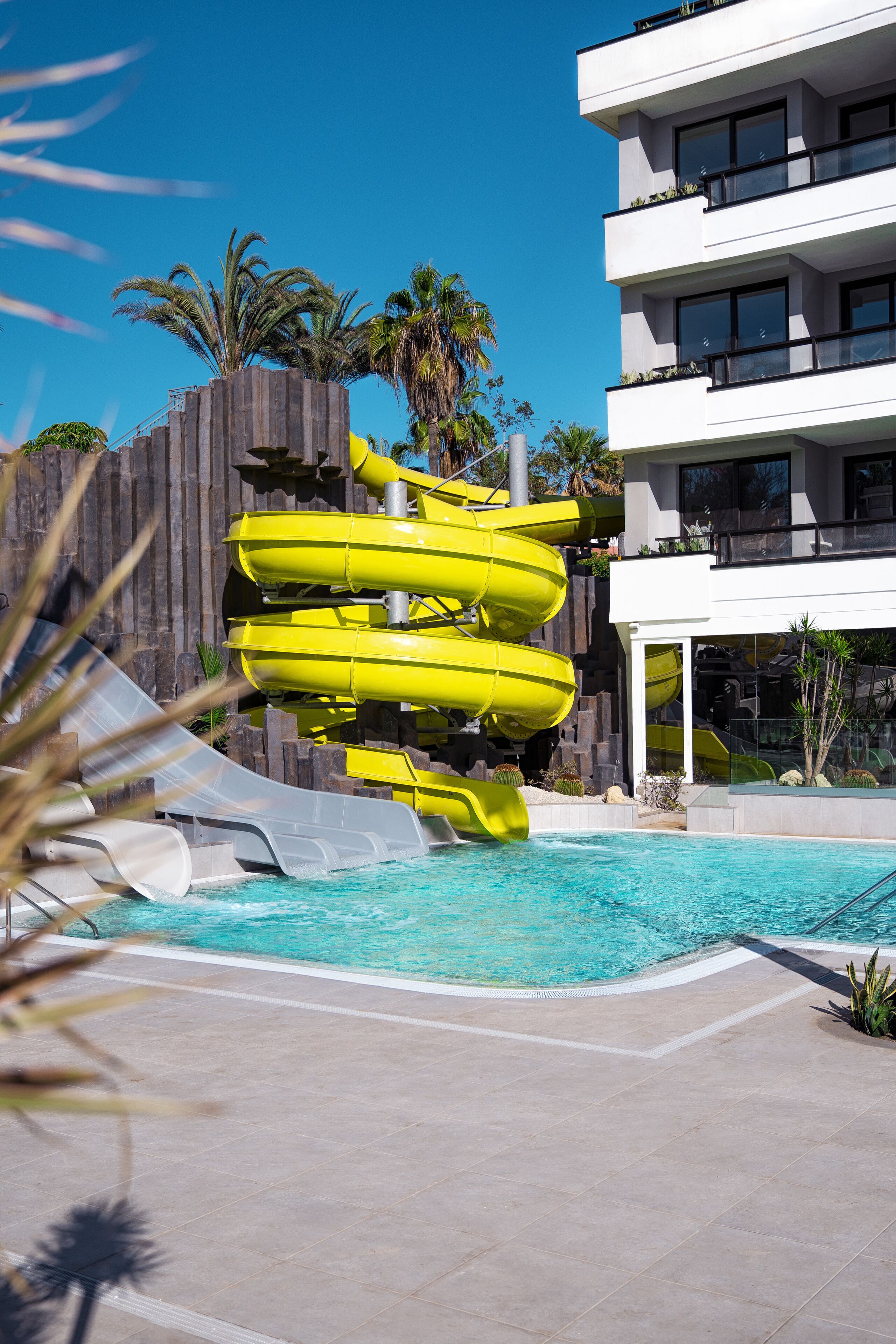 A modern hotel with a pool area featuring a water slide.