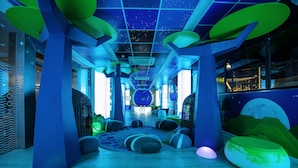 A brightly lit indoor space with a starry ceiling, large green and blue bean bags, and a circular seating area. - Spring Hotel Bitácora (Arona)