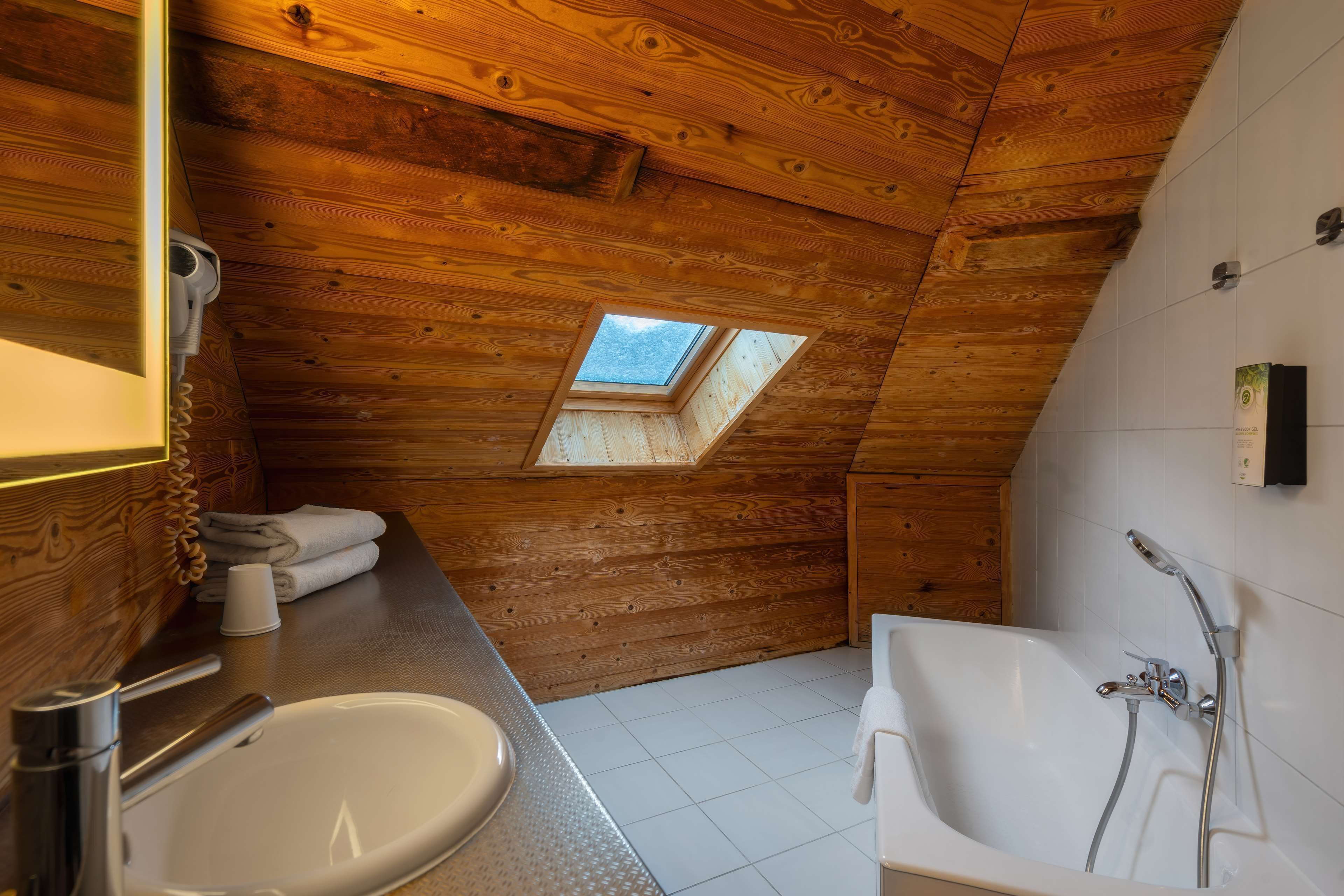 Un interior de madera con tragaluz, un lavabo y una bañera.