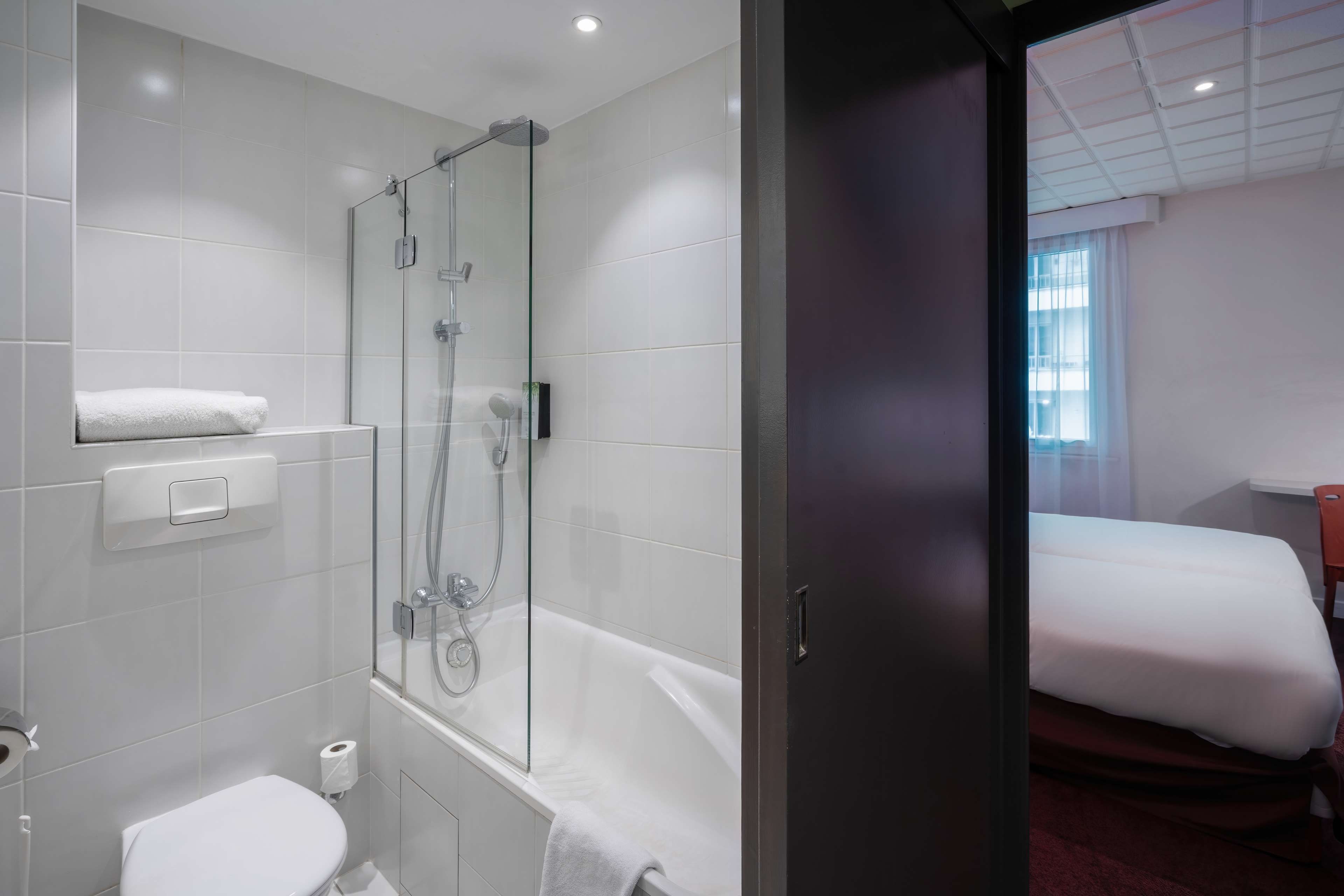 A modern bathroom with a glass-enclosed shower, a white toilet, and a bathtub.