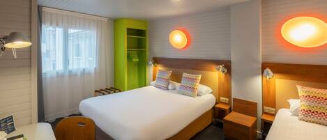 Habitación de hotel con una cama grande, mesitas de noche, un mueble de almacenamiento verde y dos lámparas de pared.