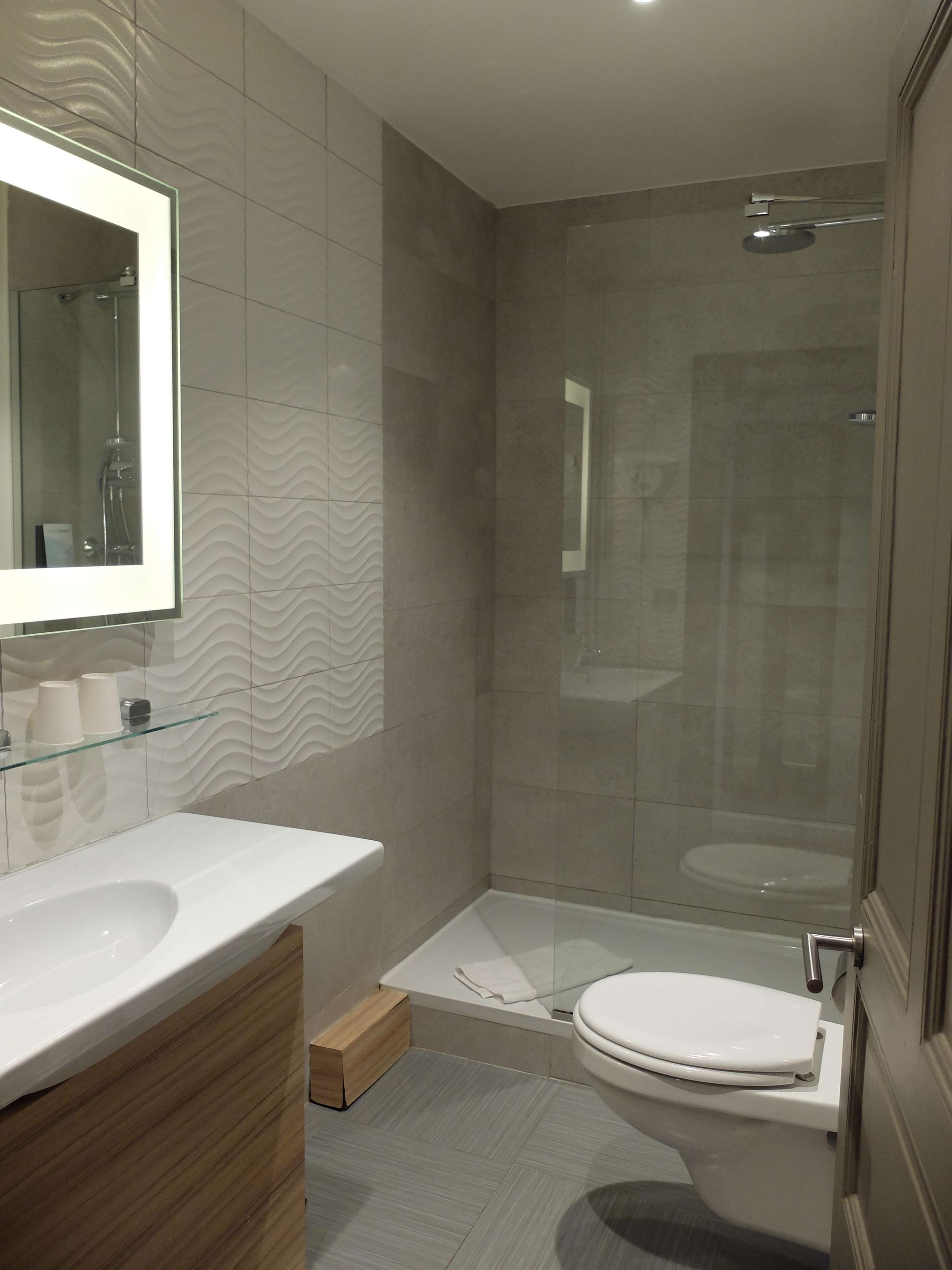 Un baño moderno con cabina de ducha de vidrio, un lavamanos blanco y un inodoro.