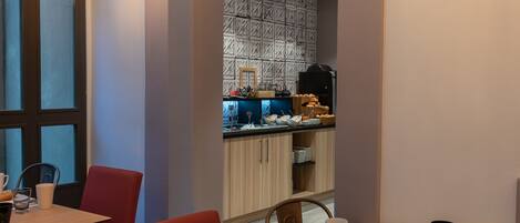 Un comedor moderno con una mesa de madera, sillas rojas y bombillas colgantes.