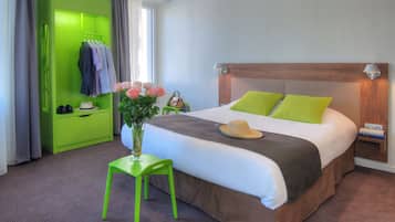 Ein Hotelzimmer mit einem Bett, einem grünen Kleiderschrank, einem Nachttisch, einem Stuhl und einer Vase mit Blumen.