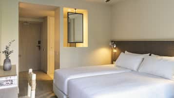 A hotel room with a bed, a desk, a chair, a mirror, and a ceiling fan.