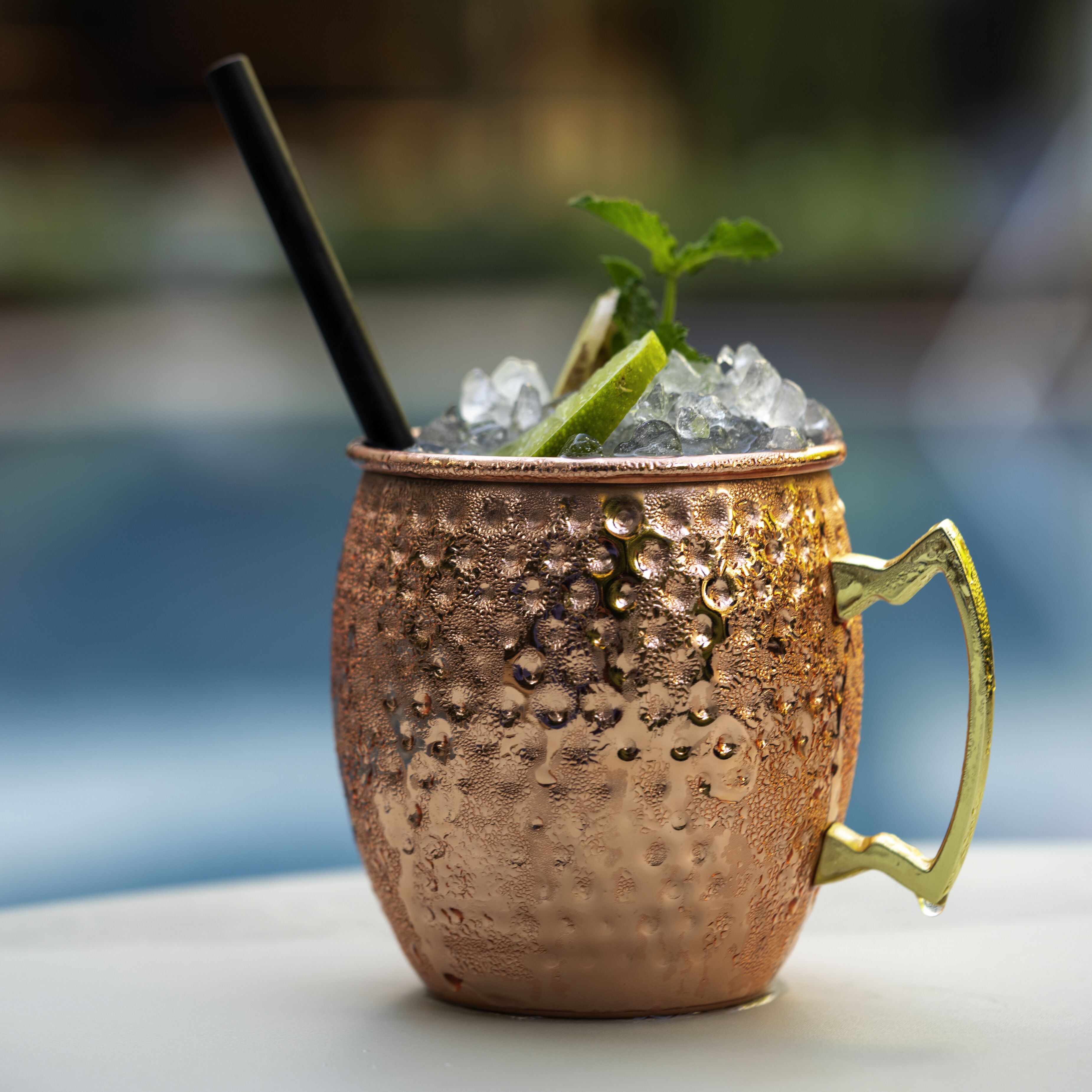 A copper mug with a handle, filled with ice and garnished with a lime wedge and mint leaves.