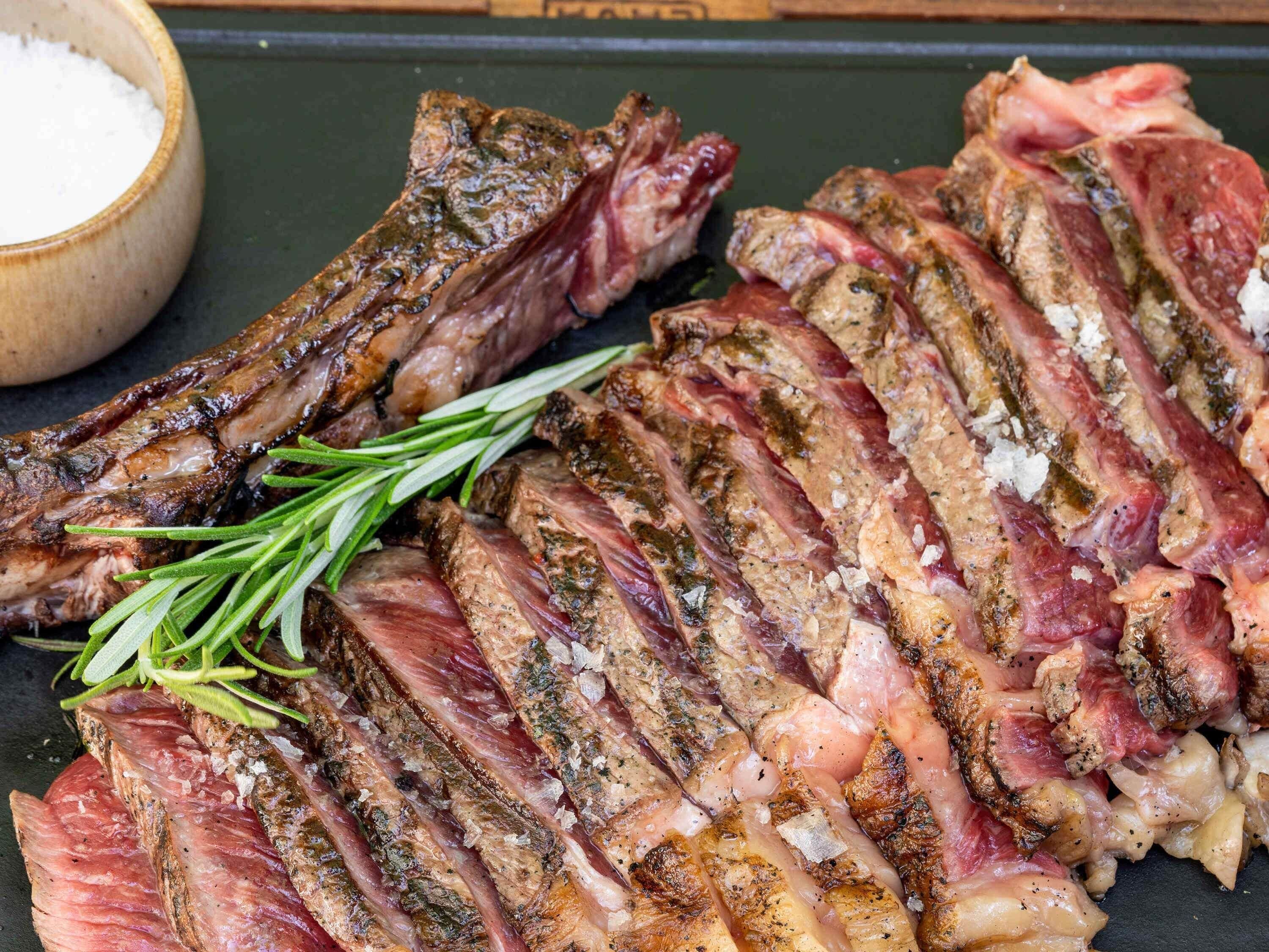 A close-up of sliced meat with herbs and salt.