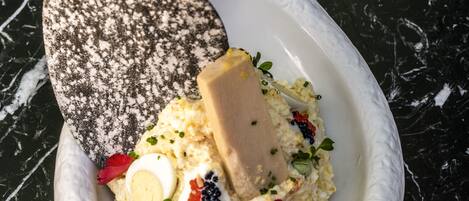 A white ceramic mortar with a textured surface containing a creamy mixture, garnished with herbs and a piece of butter.
