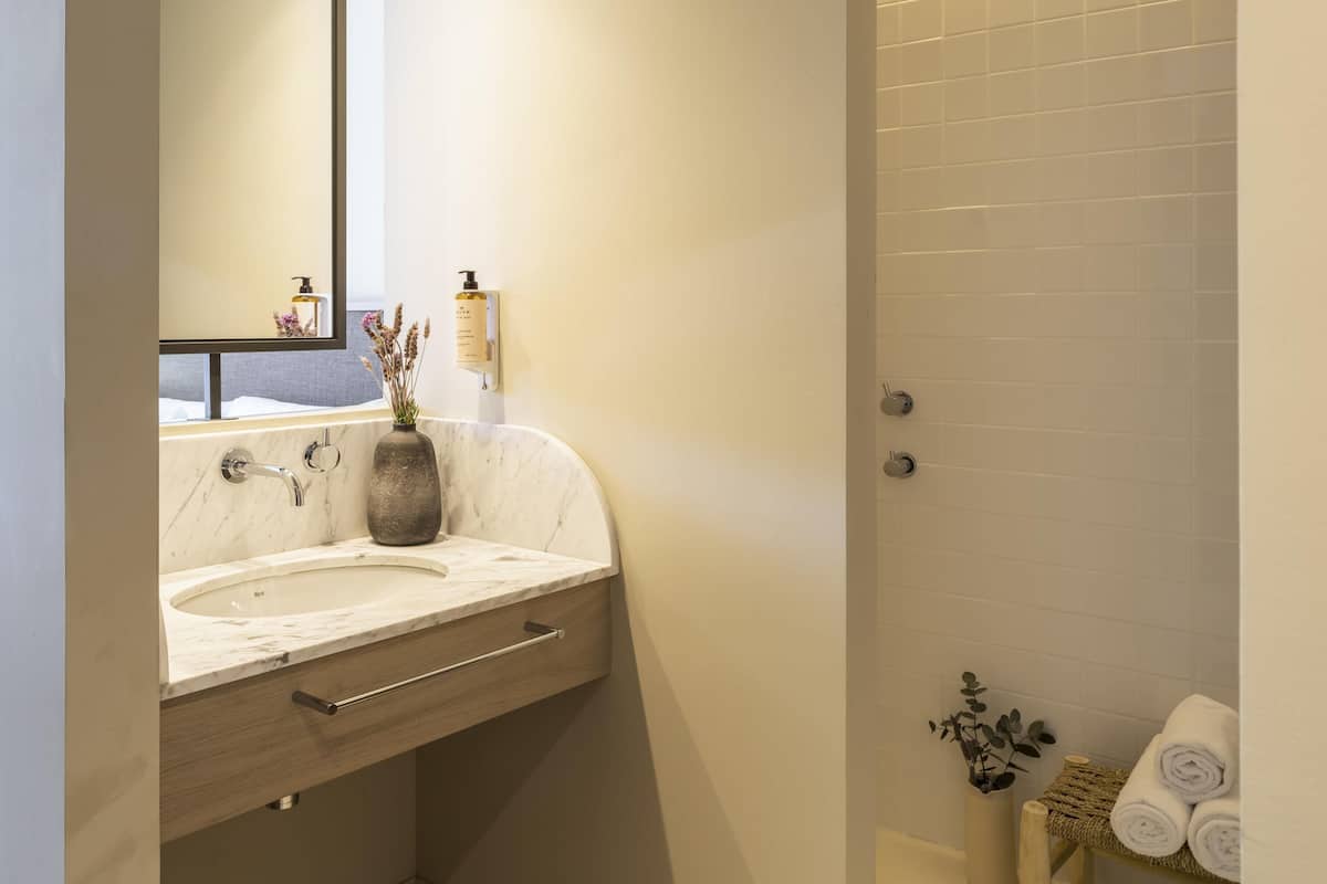 A bathroom with a marble sink, a mirror, a towel rack, and a shower area.
