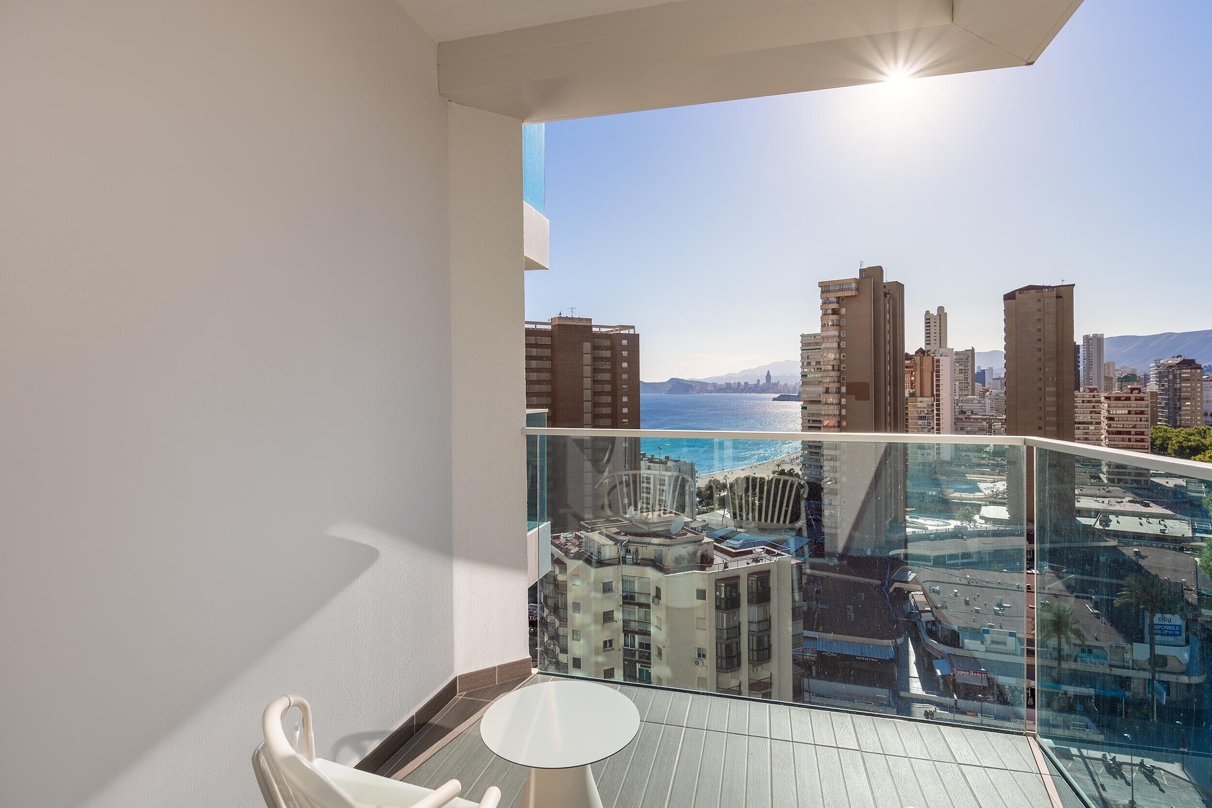 A balcony with a glass railing overlooking a cityscape and a body of water.