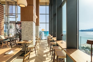 Un restaurant moderne avec de hauts plafonds, de grandes fenêtres et une vue sur la mer.