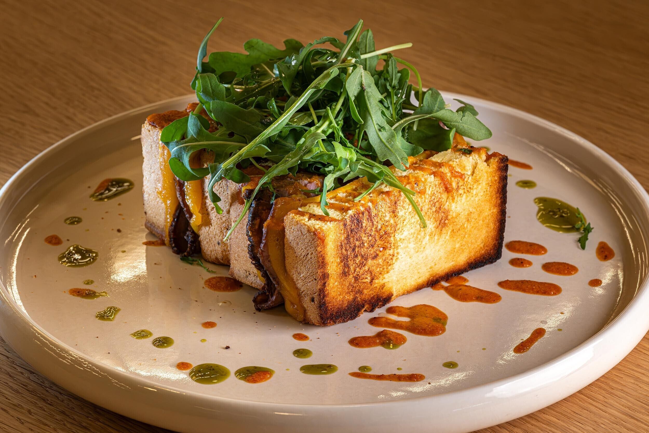 Un plato con base de pan tostado, cubierto de vegetales y salsa.