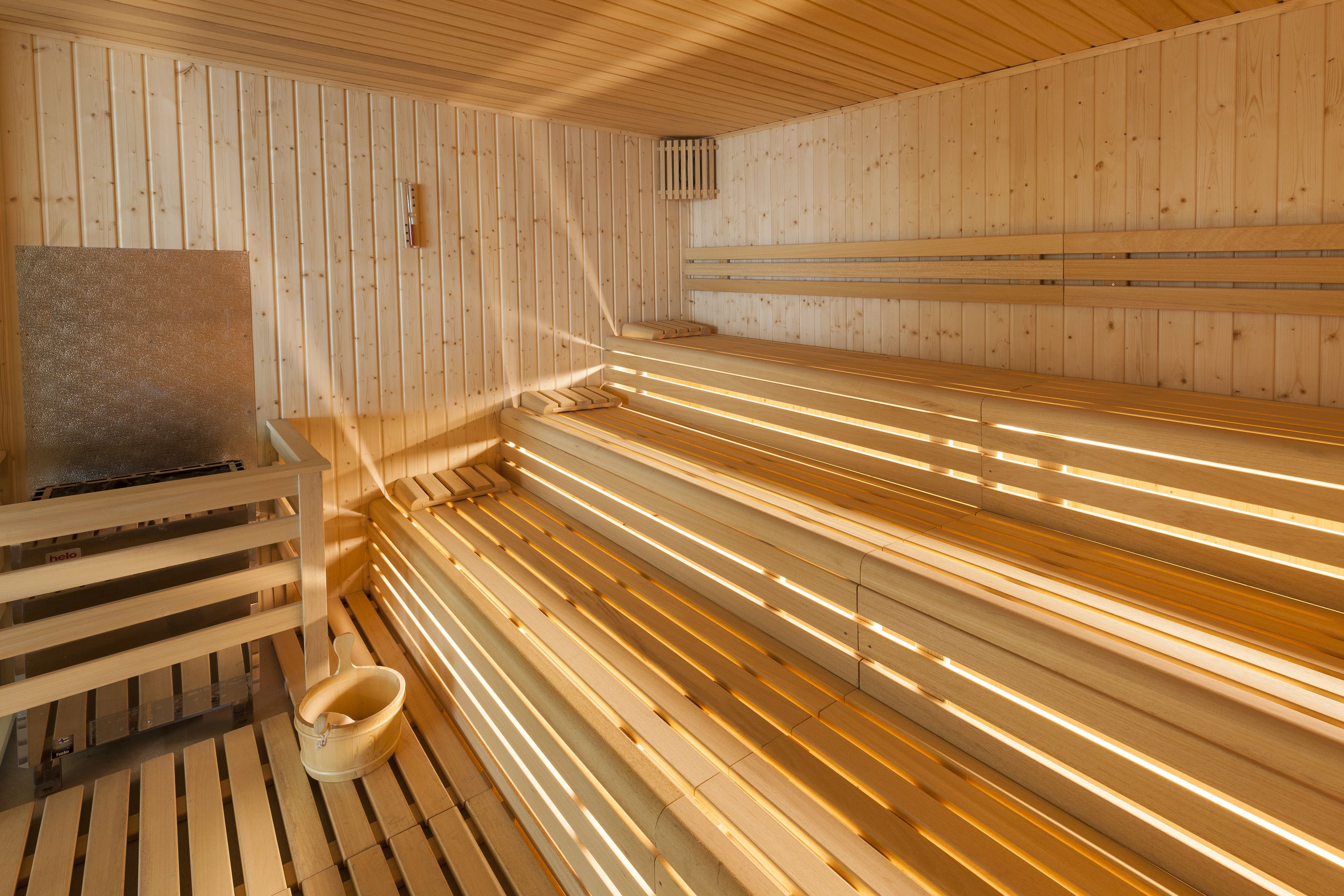 Un sauna avec des bancs en bois et un système de chauffage intégré aux bancs.