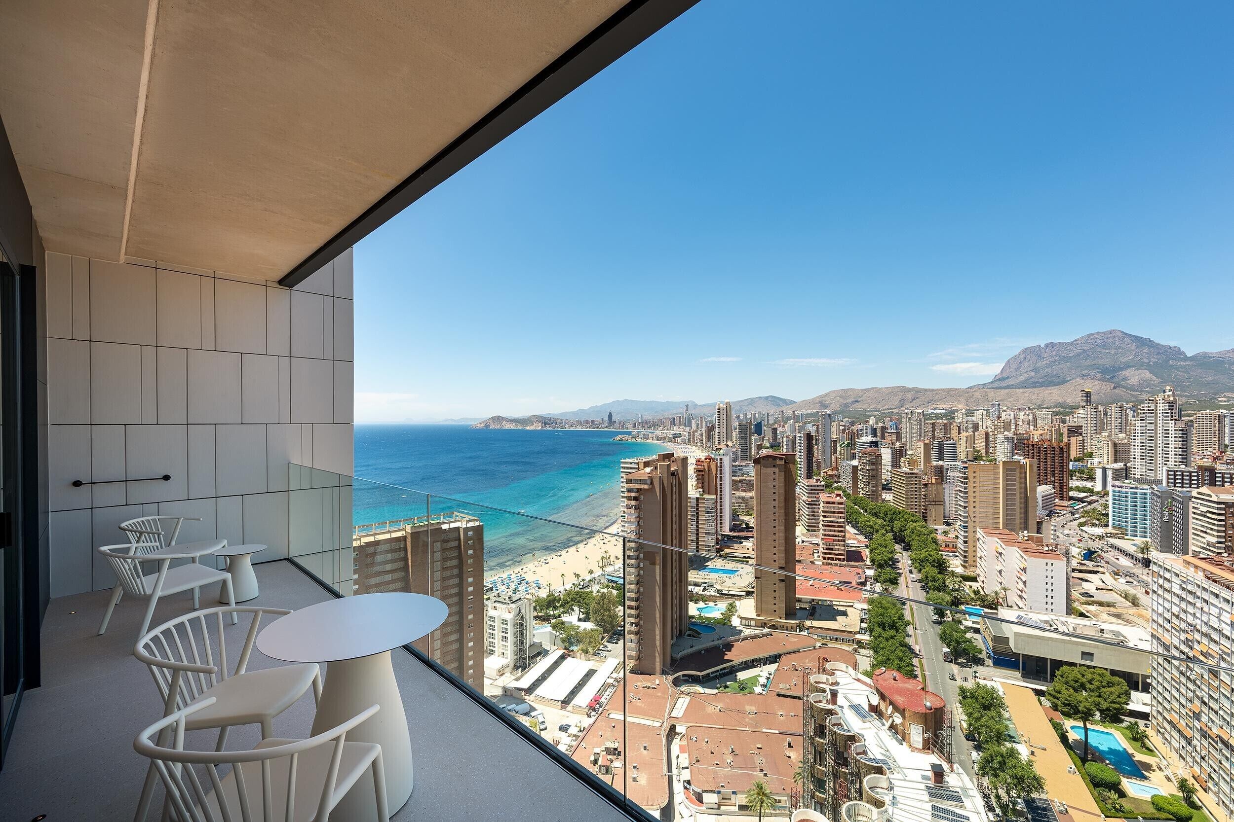 A balcony with a view of a coastal cityscape, including a beach and high-rise buildings.
