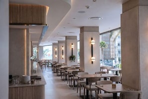 Un restaurant moderne doté d’un long comptoir, de plusieurs tables et d’un éclairage suspendu.