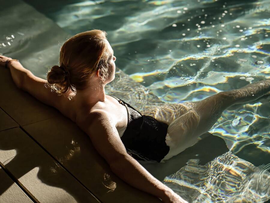A person relaxing in a clear pool with visible water ripples.