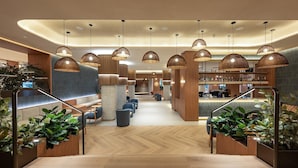 Un moderno vestíbulo de hotel con una escalera central, zonas de estar y un bar.