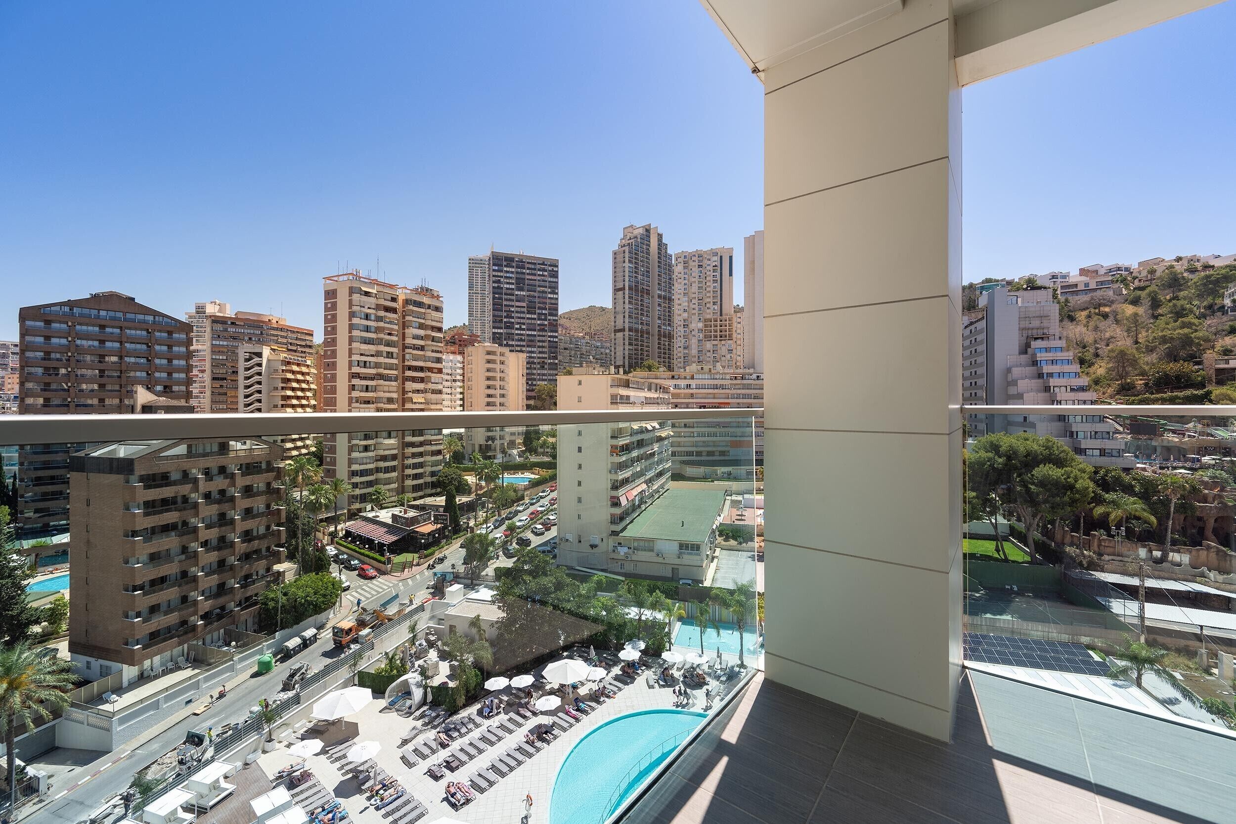 Un edificio de gran altura con varias plantas, piscina y vistas a la ciudad.