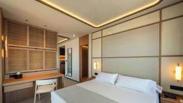 Habitación de hotel con cama, escritorio, silla e iluminación en la pared.