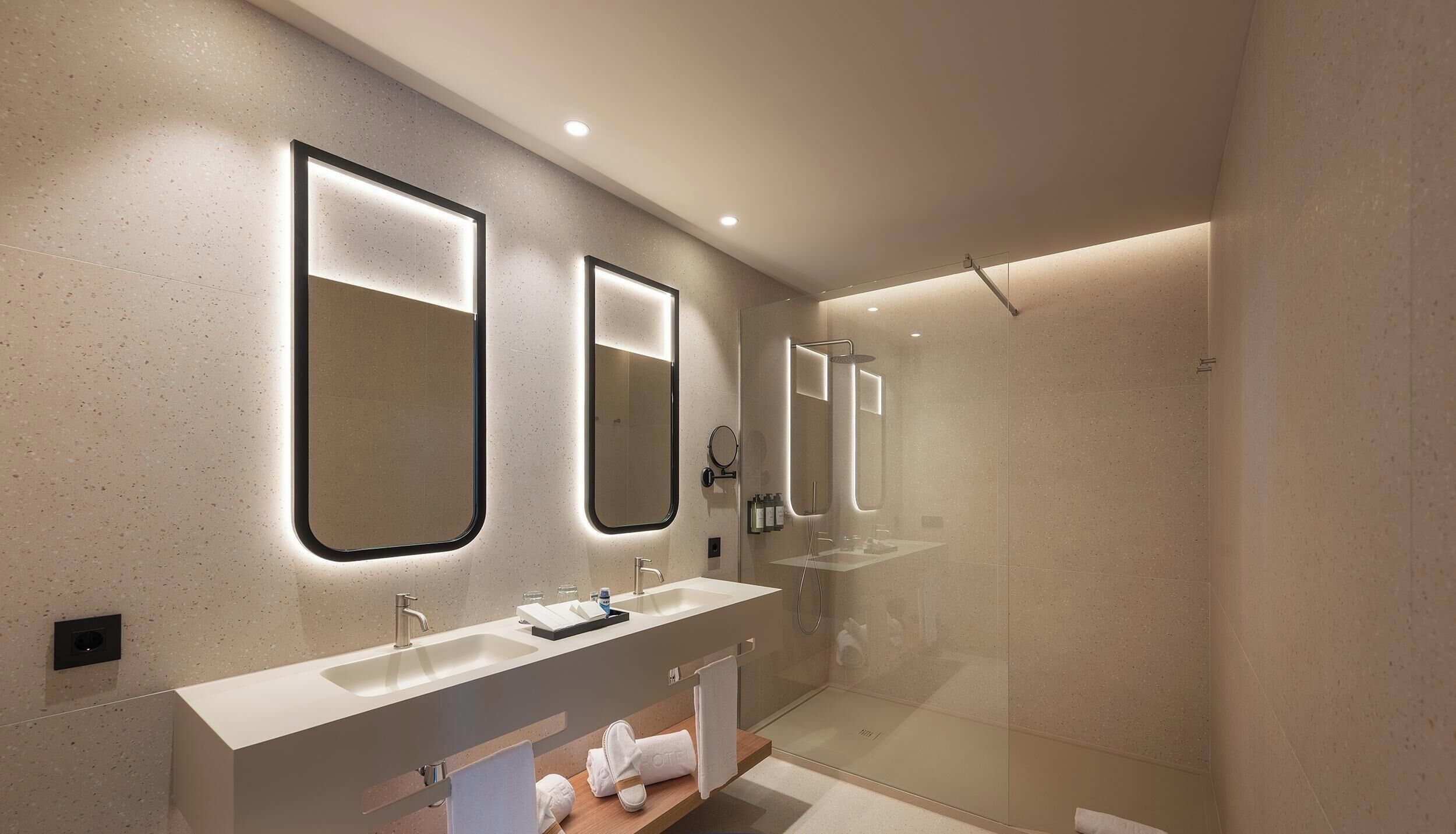 Un baño moderno con dos lavamanos, una cabina de ducha de vidrio y un espejo grande.