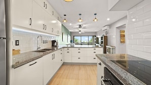 A modern kitchen with white cabinets, granite countertops, and a built-in stove. - Sand Dollar Bonaire (Kralendijk)