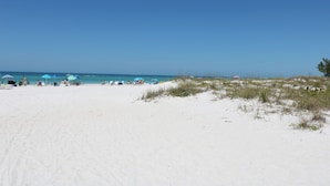 Een zanderig strand met mensen en parasols.