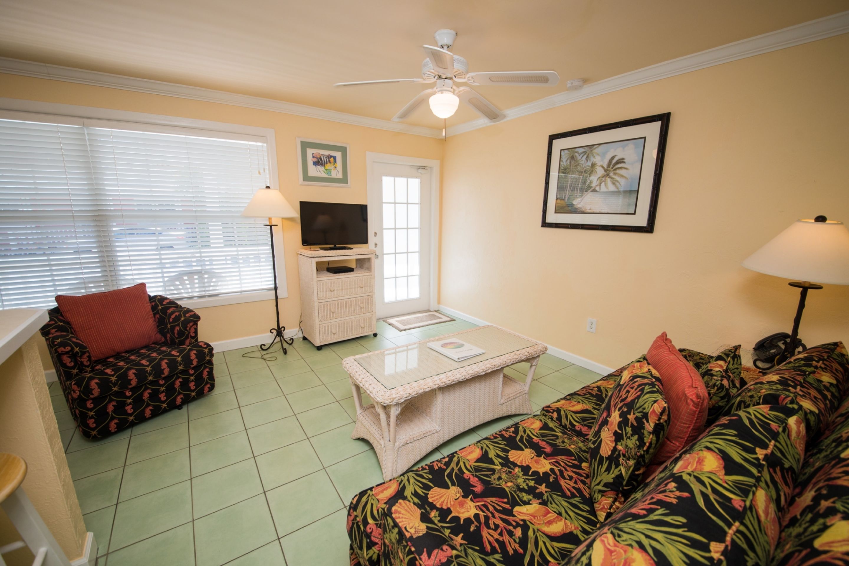 A living room with a ceiling fan, a television on a stand, a sofa, and a coffee table.