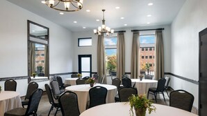 Une salle de conférence avec des tables rondes, des chaises et un lustre.
