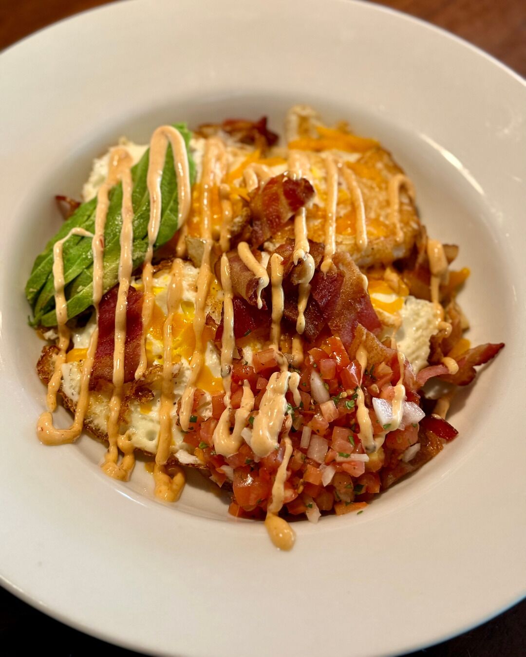 A plate of food with eggs, bacon, cheese, and a tomato-based sauce.