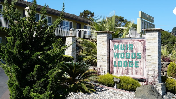 A sign for Mur Woods Lodge with a stone pillar and a wooden signboard. - Muir Woods Lodge (Mill Valley)