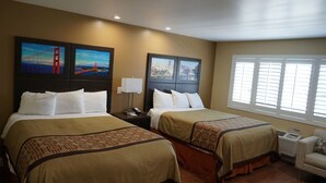 A hotel room with two beds, a nightstand with a lamp, a chair, and artwork on the walls. - Muir Woods Lodge (Mill Valley)
