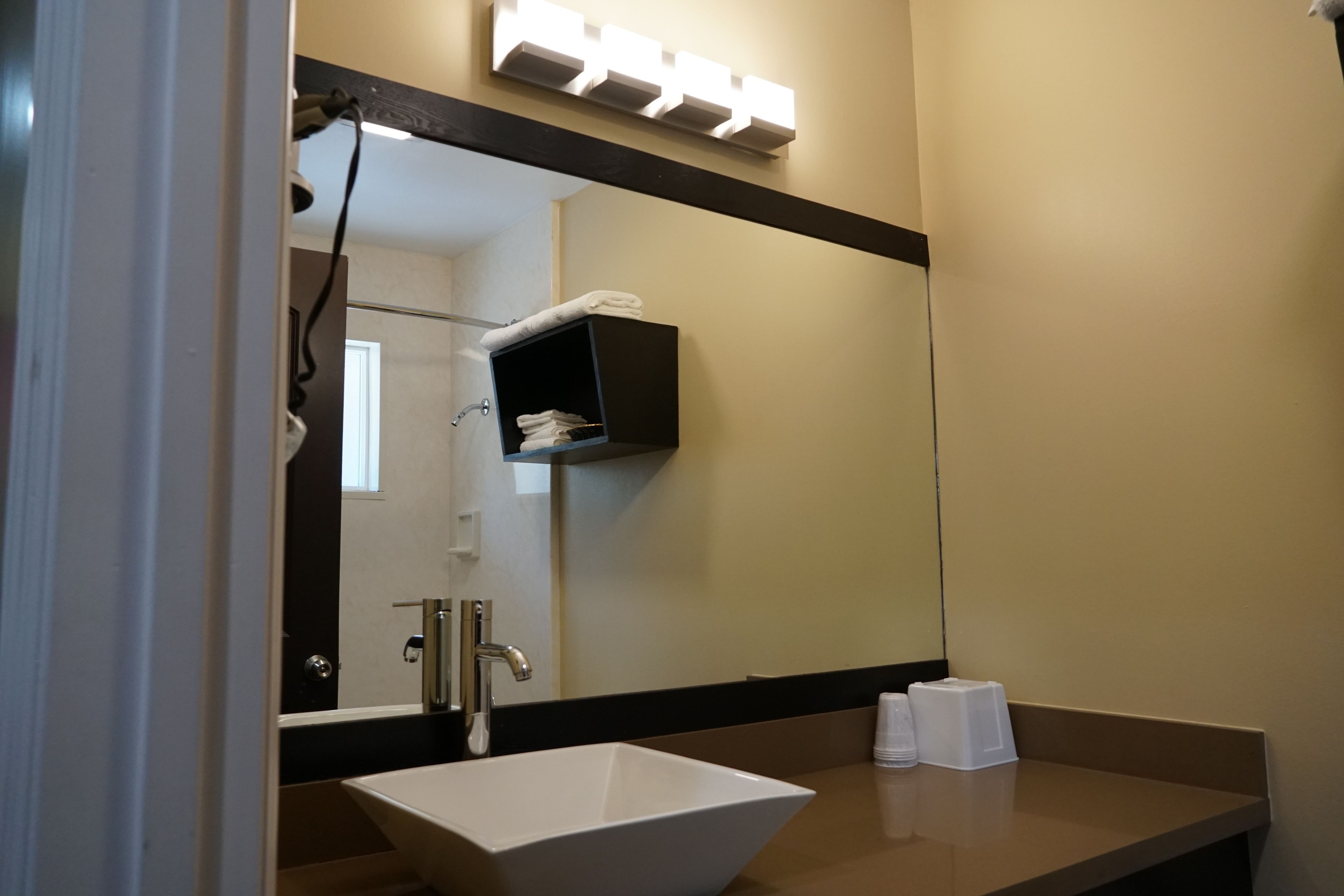 A bathroom with a large mirror, a white sink, and a towel rack.