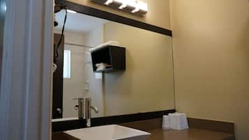 A bathroom with a large mirror, a white sink, and a towel rack.