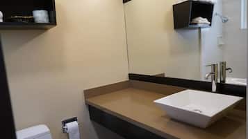 Un baño moderno con lavamanos blanco, un espejo y un perchero para toallas.