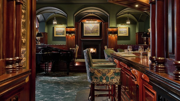 Una sala formale con un pianoforte, un caminetto e un’area bar con sedie.