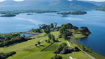 Enjoy a serene golfing experience amidst lush greenery and distant mountains, with a well-maintained course and picturesque lake views.