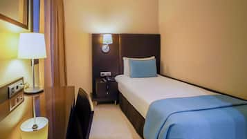 A hotel room with a bed, bedside table, lamp, and nightstand.