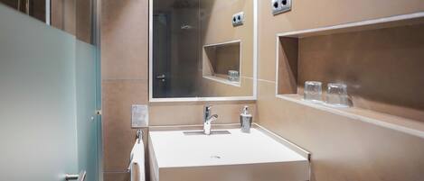 A modern bathroom with a large mirror, a white sink, and a glass shower enclosure.