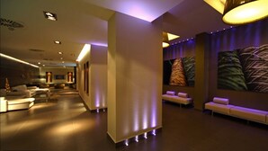 A modern lobby with a reception desk, seating area, and artwork on the walls. - Hotel Constanza (Barcelona)