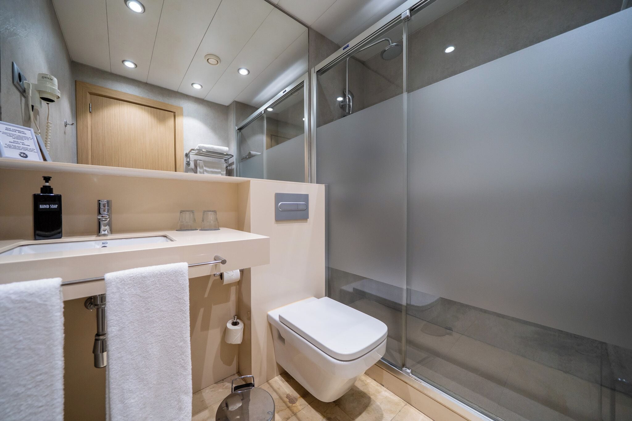 A modern bathroom with a sink, toilet, and glass shower enclosure.