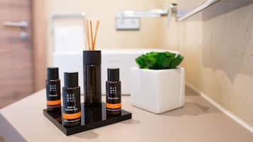 A bathroom counter with toiletries including a body lotion, shampoo, and shower gel.
