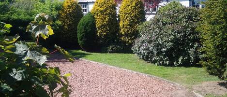 A gravel driveway leading to a house with a white exterior and a chimney.