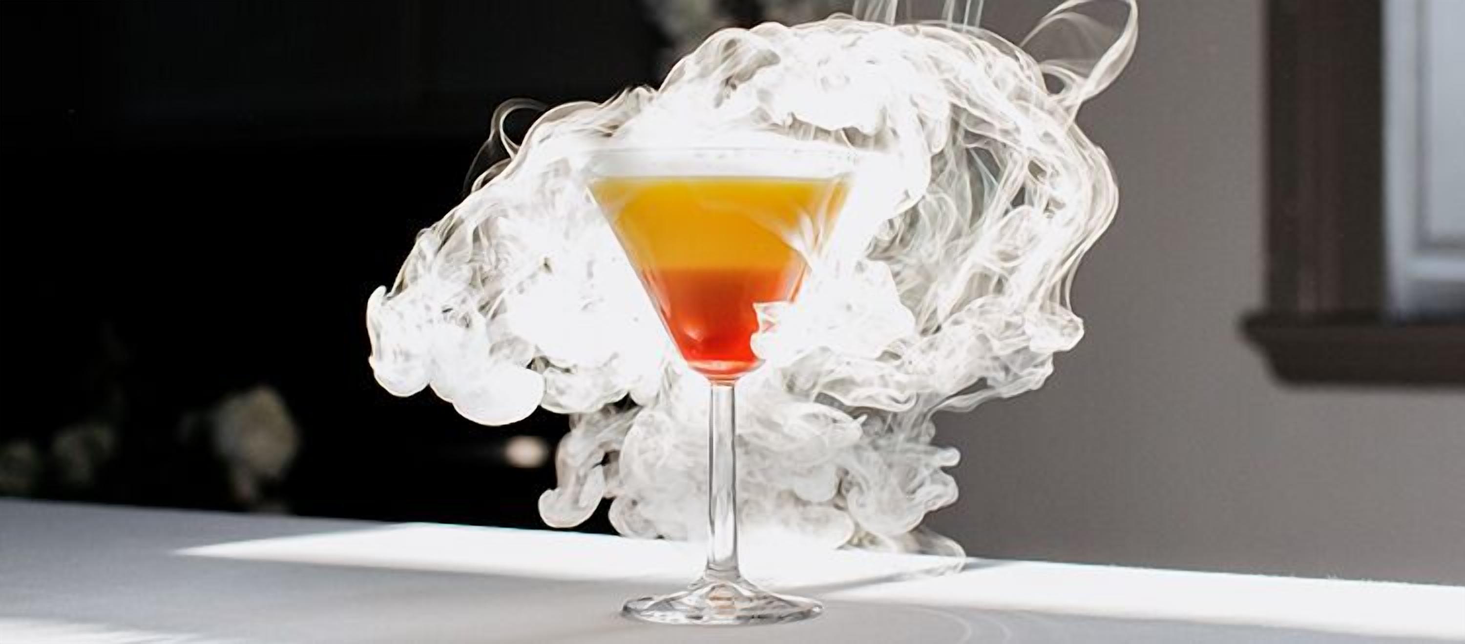 A cocktail in a martini glass with a smoky background.