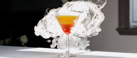 A cocktail in a martini glass with a smoky background.